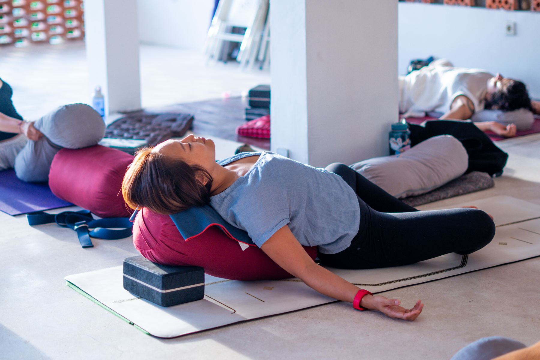 Group resting in supported Yin poses over bolsters